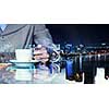 Double exposure of businesswoman hand with coffee cup and modern cityscape