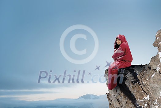 Young attractive girl in sleeping bag on peak. Mixed media Young attractive girl in sleeping bag on peak. Mixed media