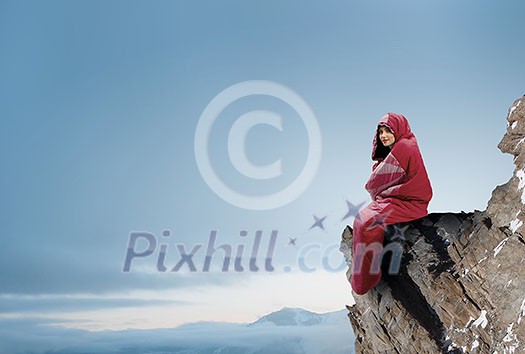 Young attractive girl in sleeping bag on peak. Mixed media