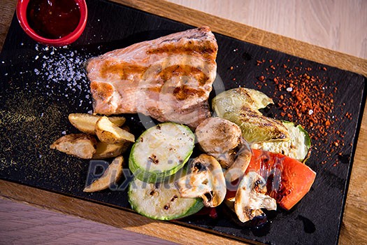 Juicy grilled steak with vegetables on a wooden board Juicy grilled steak with vegetables on a wooden board