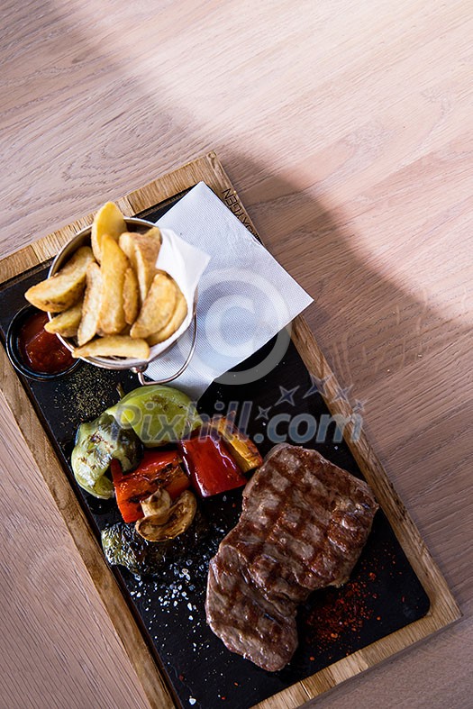 Juicy grilled steak with vegetables on a wooden board