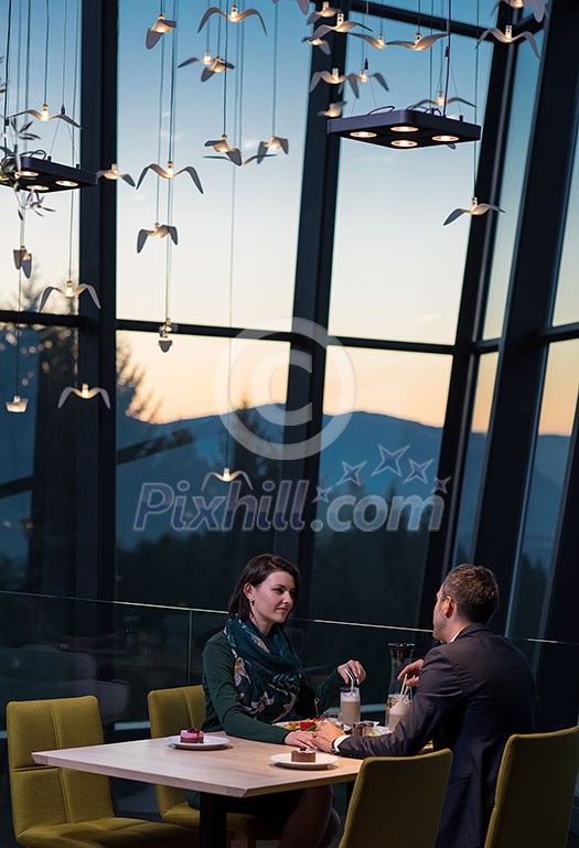 young happy loving couple enjoying romantic dinner while celebrating Valentines day near the window at luxury restaurant young happy loving couple enjoying romantic dinner while celebrating Valentines day near the window at luxury restaurant