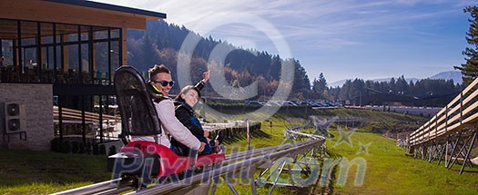 Excited young couple driving alpine coaster while enjoying beautiful sunny day in the nature Excited young couple driving alpine coaster while enjoying beautiful sunny day in the nature