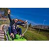 Excited young father and son driving on alpine coaster while enjoying beautiful sunny day in the nature