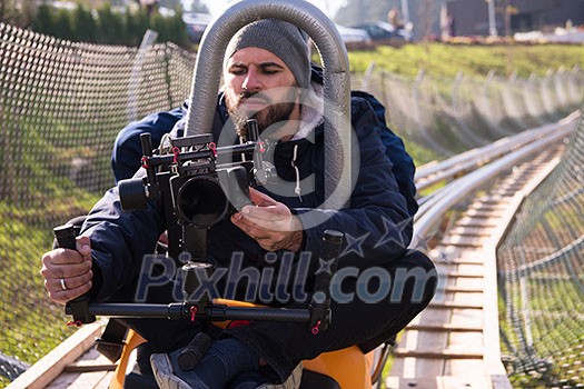 young videographer with gimball video slr at work on alpine coaster young videographer with gimball video slr at work on alpine coaster