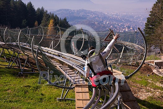Excited young couple driving alpine coaster while enjoying beautiful sunny day in the nature
