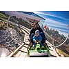 Excited young father and son driving on alpine coaster while enjoying beautiful sunny day in the nature