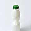 White empty bottle mockup with green top for dairy products on a light gray background, copy space.