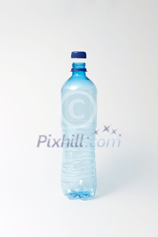 Empty transparent plastic bottle with blue cap on a light gray background, copy space. Mock up. Empty transparent plastic bottle with blue cap on a light gray background, copy space. Mock up.