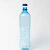 Empty transparent plastic bottle with blue cap on a light gray background, copy space. Mock up.