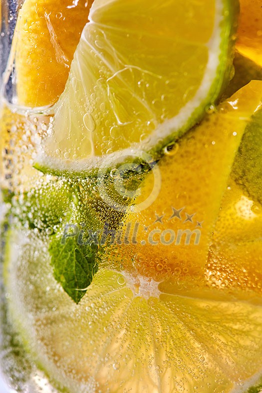 In a clear glass mint leaf, slices of lime and lemon with bubbles. Macro photo of summer cooling mojito In a clear glass mint leaf, slices of lime and lemon with bubbles. Macro photo of summer cooling mojito