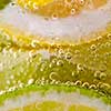 Pieces of citrus fruits of lemon and lime with bubbles in a glass of water. Macro photo of summer drink