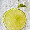 Fresh mint leaf and a slice of lime with bubbles in a glass with ice. Macro photo of refreshing drink