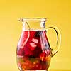 Freshly made berry fruit drink in a glass jug on a yellow background with copy space. Summer vitamin beverage