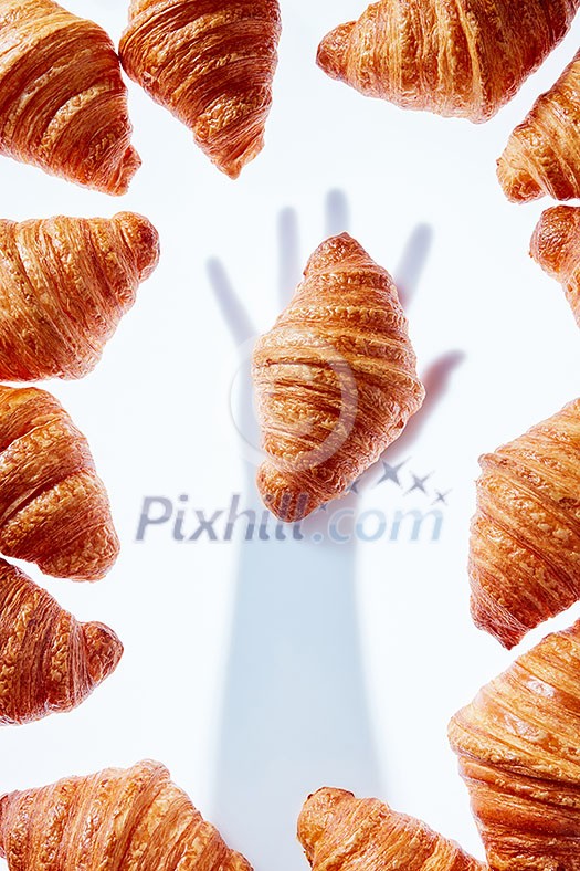 Pastry frame with shadow from hand taling fresh homemade french croissant on a light gray background. Place for text. Pastry frame with shadow from hand taling fresh homemade french croissant on a light gray background. Place for text.
