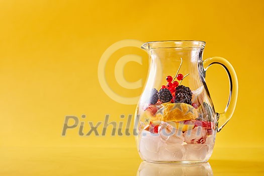 Preparation of homemade refreshing cold fruit punch in a glass jar on an yellow background, copy space. Concept of cold nonalcoholic summer drinks. Preparation of homemade refreshing cold fruit punch in a glass jar on an yellow background, copy space. Concept of cold nonalcoholic summer drinks.