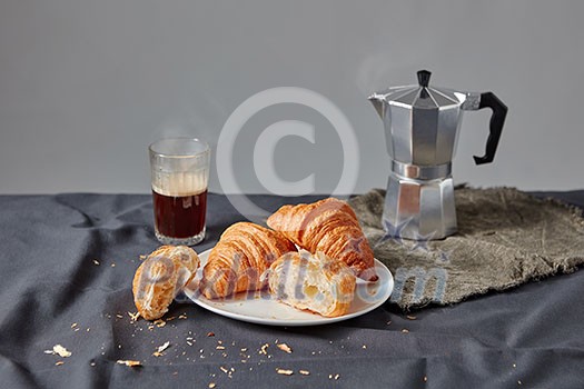 Morning breakfast with french homemade crunchy homemade croissants on a plate with freshly brewed fragrant coffee on a dark textile background. Copy space. Morning breakfast with french homemade crunchy homemade croissants on a plate with freshly brewed fragrant coffee on a dark textile background. Copy space.
