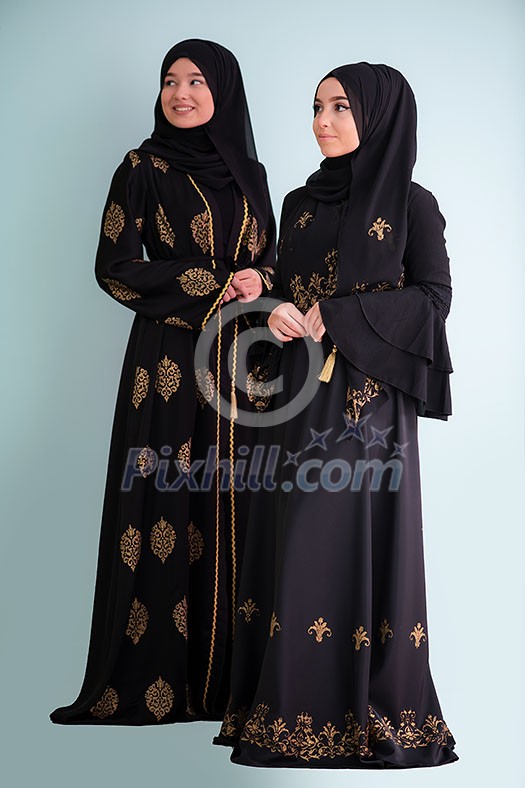 beautiful muslim woman in fashinable dress with hijab isolated on cyan background   representing concept of modern  islam fashion with mix of traditional elements and ramadan kareem clothes