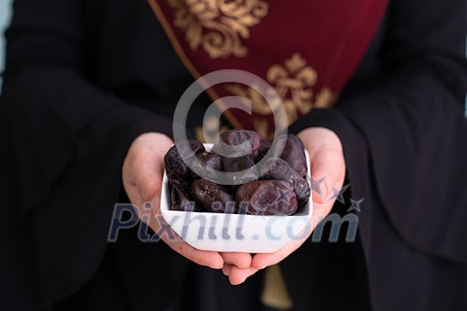 modern muslim woman holding a plate full of sweet dates on iftar time in ramadan kareem islamic healthy food concept