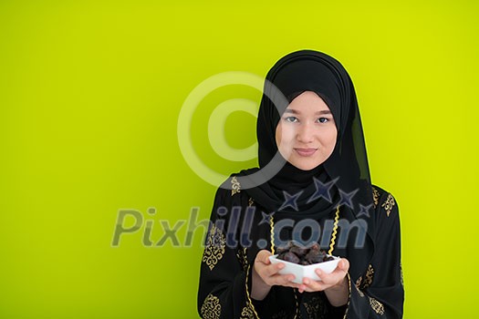 modern muslim woman holding a plate full of sweet dates on iftar time in ramadan kareem islamic healthy food concept ufo green background