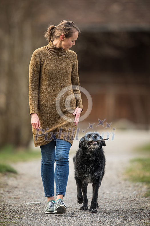 Young woman walking her dog after work in a park