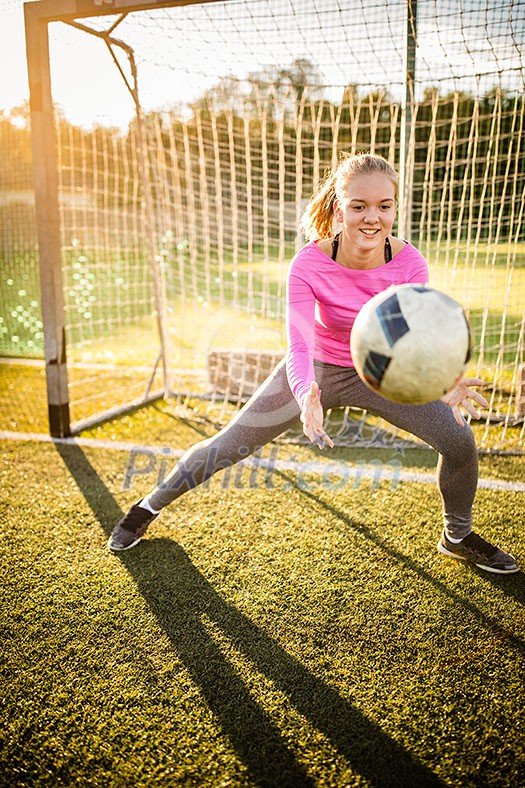 Teen female goalie catching a shot during a soccer game