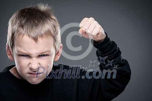 Loads of aggression in a little boy - education concept hinting behavioral problems in young children (shallow DOF) - little boy with hands clenched into fists about to punch someone