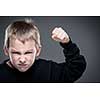 Loads of aggression in a little boy - education concept hinting behavioral problems in young children (shallow DOF) - little boy with hands clenched into fists about to punch someone