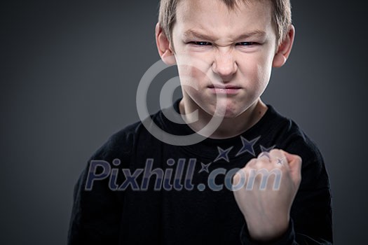 Loads of aggression in a little boy - education concept hinting behavioral problems in young children (shallow DOF) - little boy with hands clenched into fists about to punch someone