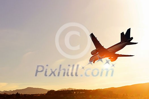 Airplane flying in air against sunset background