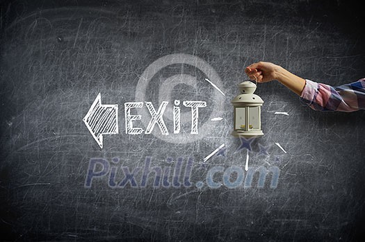 Hand of person holding lantern against chalkboard background