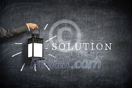 Hand of person holding lantern against chalkboard background Hand of person holding lantern against chalkboard background