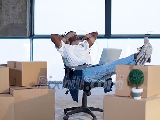 young african american male architect taking a break on construction site while checking documents and business workflow with cardboard boxes around him in new startup office young african american male architect taking a break on construction site while checking documents and business workflow with cardboard boxes around him in new startup office