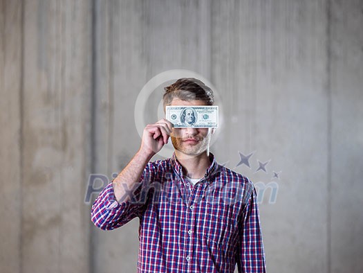 business, people and finances concept  happy young business man holding american dollars banknote over the eyes  in new startup office