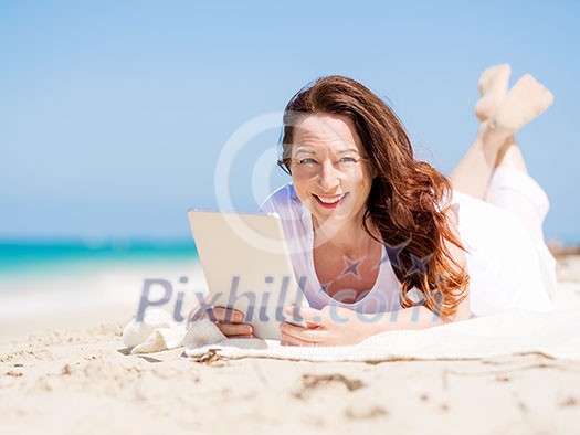 Woman in white clothes on the beach with tablet