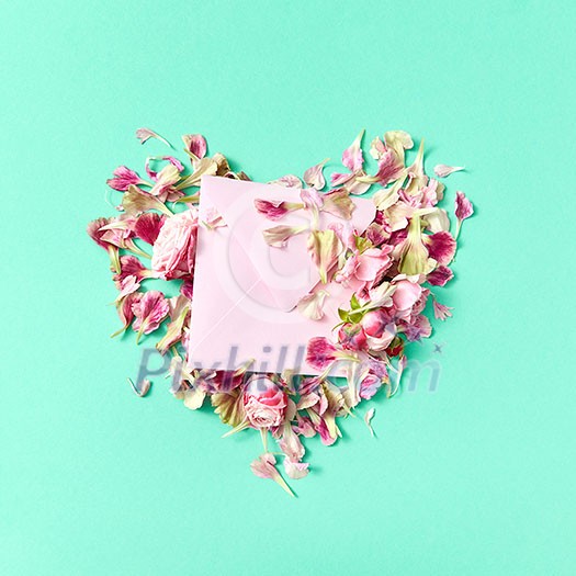 Congratulation card with floral heart from roses and craft envelope on a light turquoise background, place for text. Top view. Congratulation card with floral heart from roses and craft envelope on a light turquoise background, place for text. Top view.