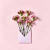 Handmade blank envelope with bouquet of carnations flowers on a pastel pink background, copy space. Top view. Congratulation card.
