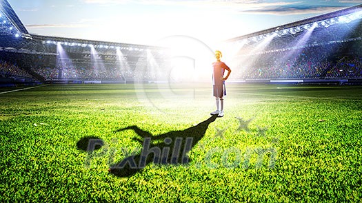 Little soccer champion on green field and his shadow on grass. Mixed media