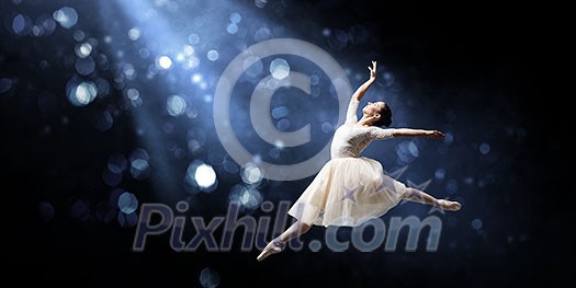 Elegant woman dancer in white dress against dark background