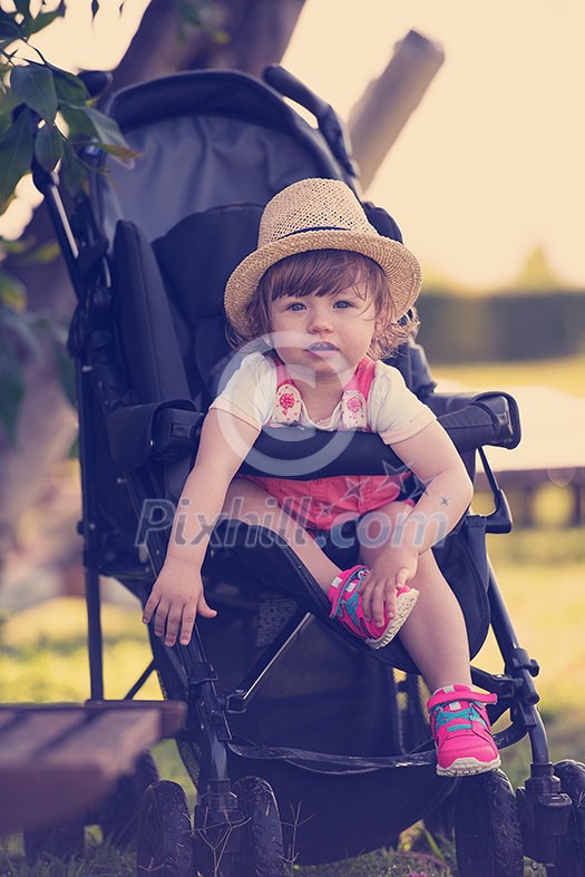 little and very beautiful baby girl sitting in the baby stroller and waiting for mom little and very beautiful baby girl sitting in the baby stroller and waiting for mom