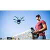 Handsome young man flying a drone outdoors using a VR/augmented reality glasses to operate the device, to see in real time the video feed from the drone