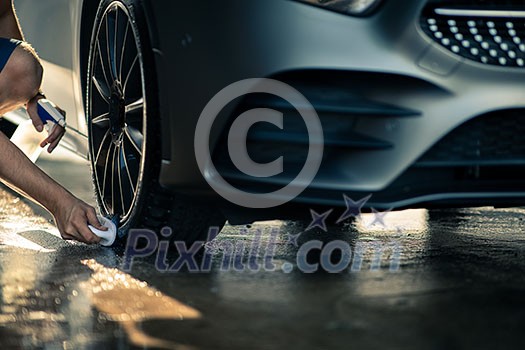 Car in a car wash - brand new car owner detailing his lovely wheels Car in a car wash - brand new car owner detailing his lovely wheels
