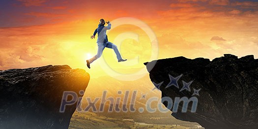 Afroamerican man jumping over gap against sunrise background. Mixed media