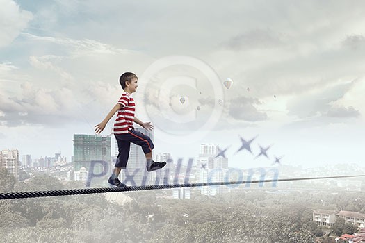 Cute little boy walking on rope high in sky