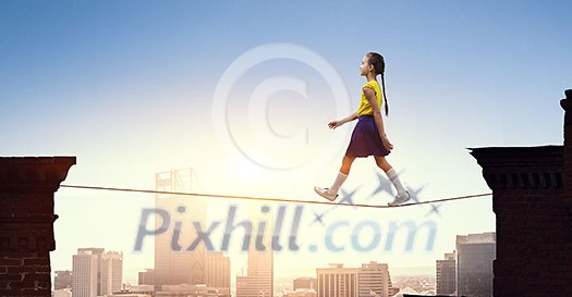 Cute little girl walking on rope high in sky Cute little girl walking on rope high in sky