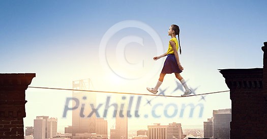 Cute little girl walking on rope high in sky