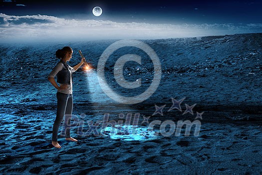 Woman with flashlighter in hand walking in darkness. Mixed media Woman with flashlighter in hand walking in darkness. Mixed media
