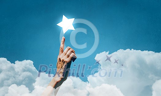 Human hand touching with finger star in sky