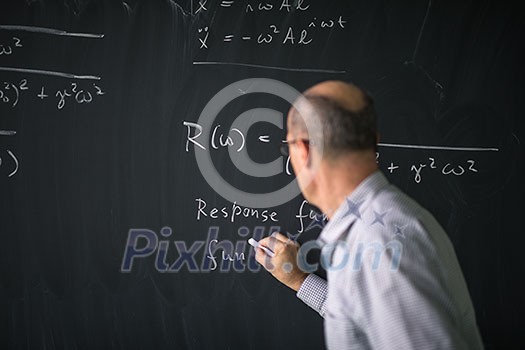 Math teacher drawing   fuction graph on a blackboard during mathclass (shallow DOF, color toned image)