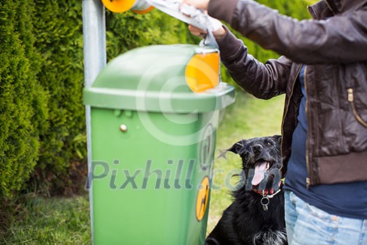 Do not let your dog foul! - Young woman grabbing a plastic bag in a park to tidy up after her dog later Do not let your dog foul! - Young woman grabbing a plastic bag in a park to tidy up after her dog later